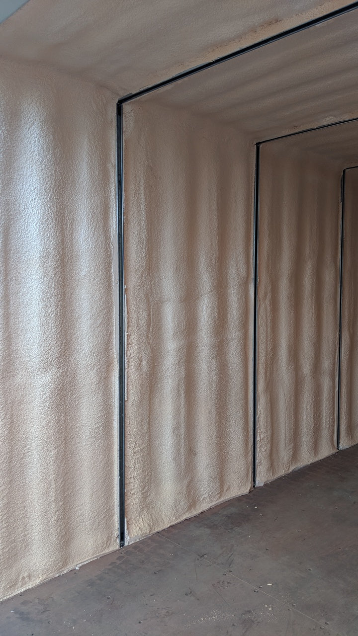 Interior close-up of a spray foam insulated shipping container, showing smooth foam application along corrugated steel walls for enhanced thermal performance and moisture control.