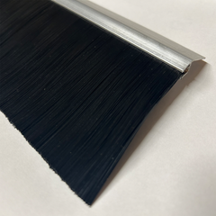 Close-up image of a black brush seal with an aluminum mounting strip, designed for roll-up door framing kits. The dense synthetic bristles are shown in detail, highlighting their effectiveness in sealing gaps and preventing dust, pests, and water intrusion.