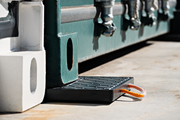 Container corner pads installed under shipping container corners on paved surface