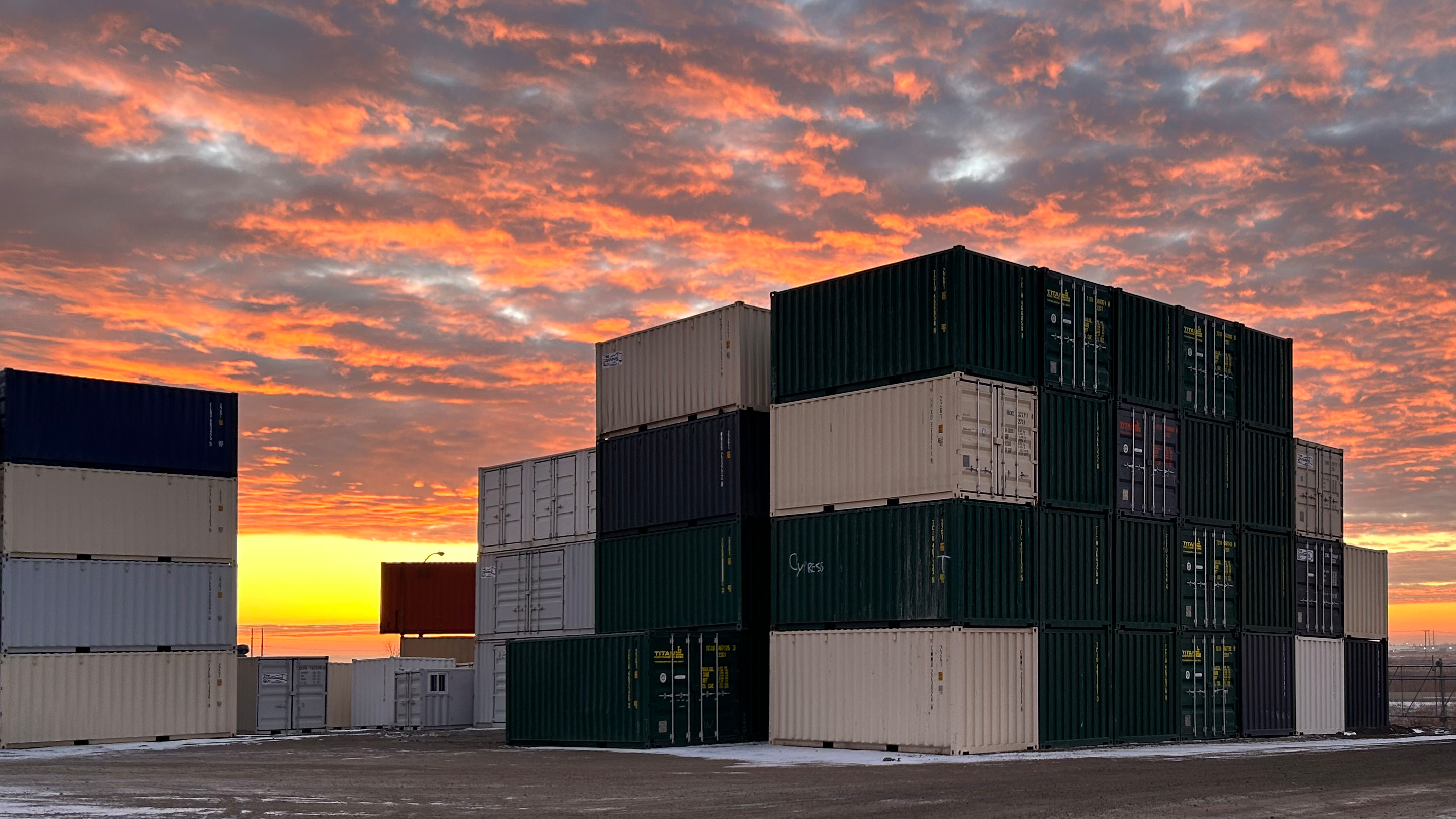 Shipping containers stacked in The Container Guy depot at sunset